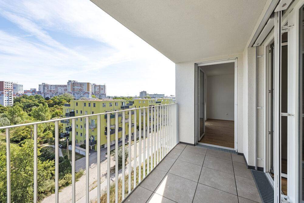 Geräumiger Balkon mit Fliesenboden und weitem Blick über die Stadt und grüne Umgebung.