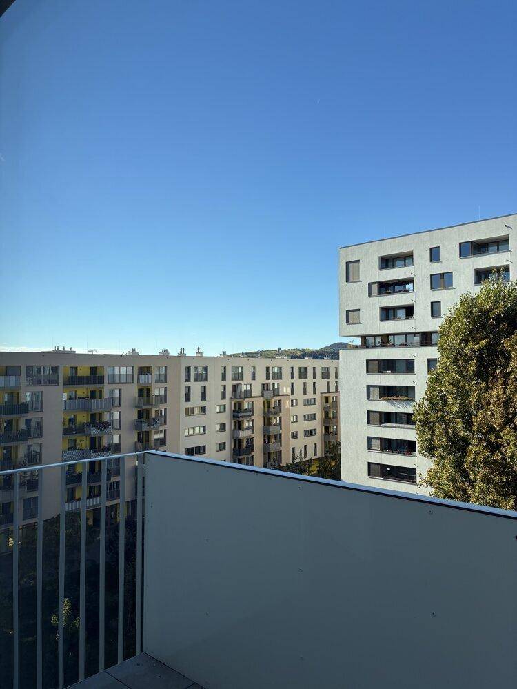 Blick vom Balkon auf moderne Wohngebäude und die umliegende städtische Landschaft.