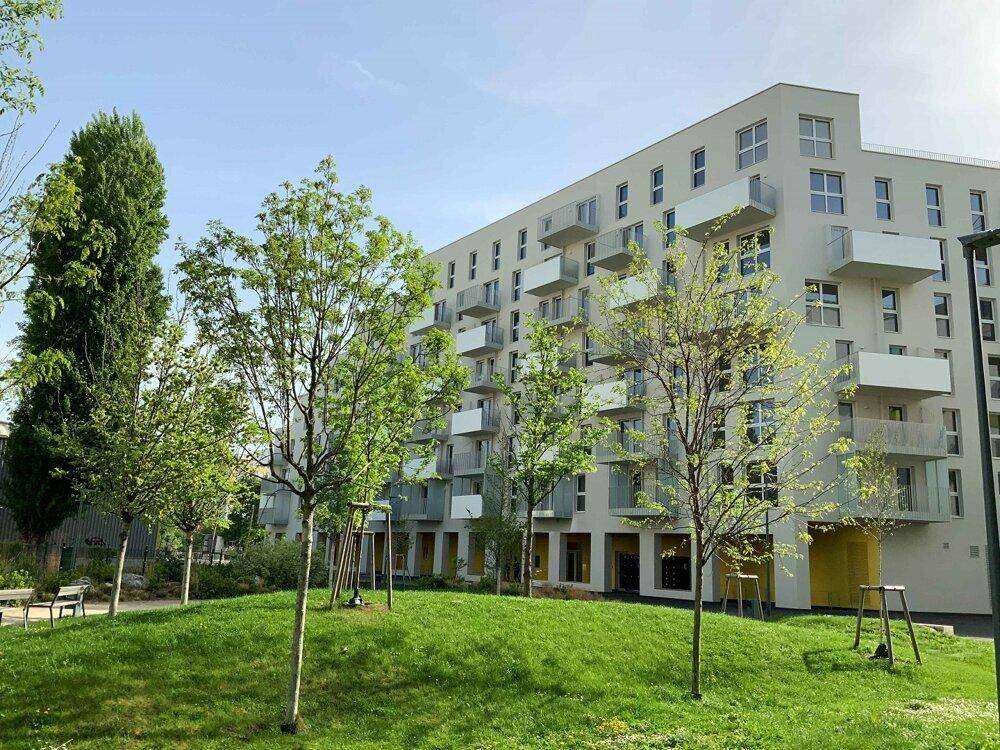Moderne Wohnanlage mit vielen Balkonen, umgeben von jungen Bäumen und einer gepflegten Rasenfläche.