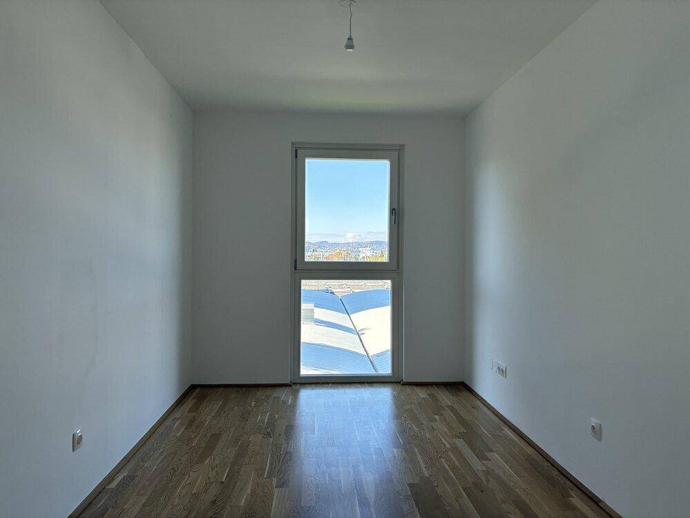 Ruhiges Zimmer mit Parkettboden und Fenster, ideal als Schlafzimmer.