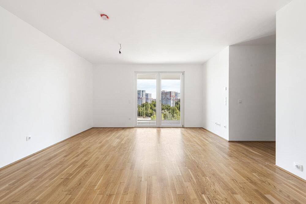 Helles Wohnzimmer mit Holzboden und großen Fenstern, die einen weiten Blick bieten.
