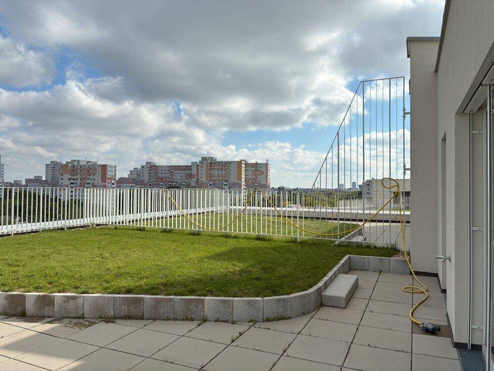 Dachterrasse mit Rasen und gepflasterten Flächen, bietet einen weiten Blick über die Stadt.