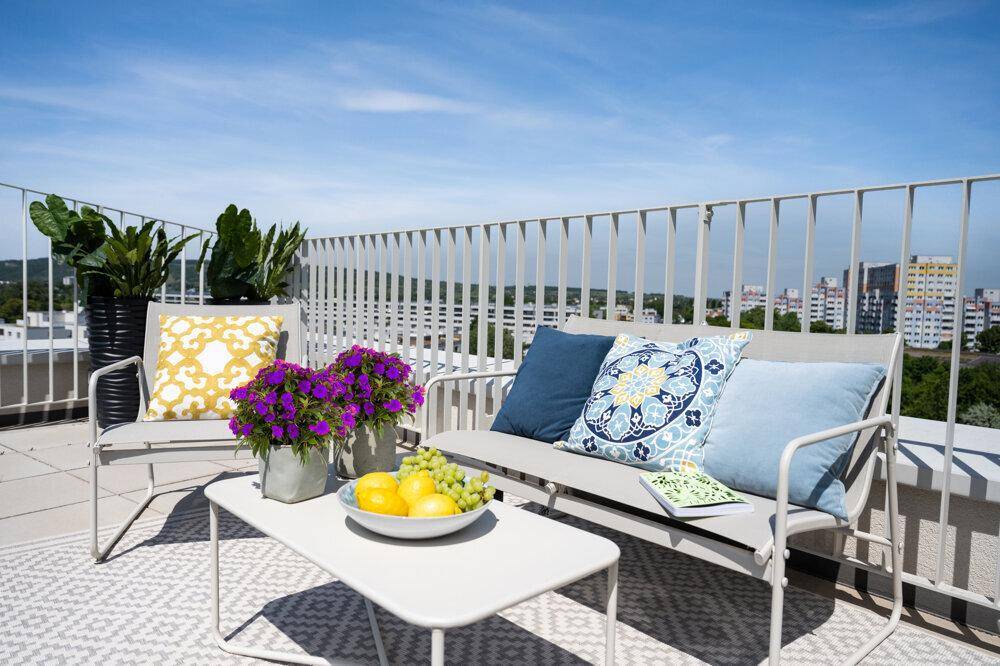 Gemütliche Dachterrasse mit stilvollen Gartenmöbeln, bunten Kissen und Panoramablick auf die Stadt.