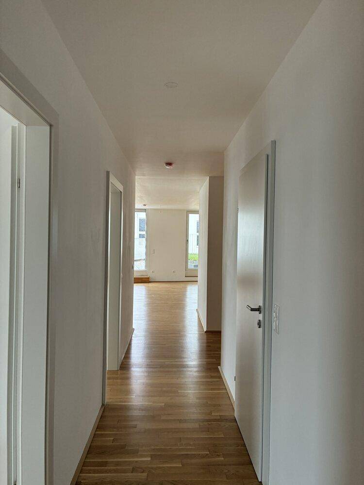 Heller Flur mit Parkettboden, der zu den weiteren Räumen der Wohnung führt.