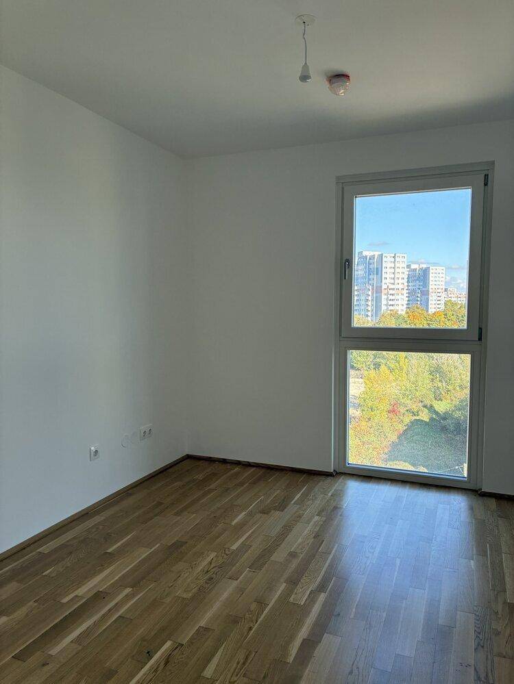 Geräumiges Schlafzimmer mit Parkettboden und viel Tageslicht durch ein großes Fenster.