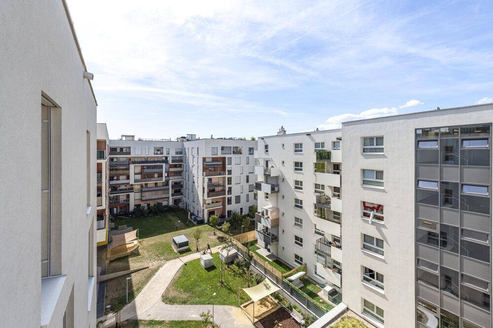 Großer Balkon mit Fliesenboden und Panoramablick auf den Innenhof und die Nachbargebäude.