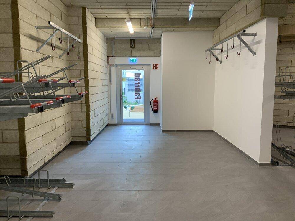 Geräumiger Fahrradraum mit vielen Abstellmöglichkeiten und Zugang nach draußen in einem Neubau.