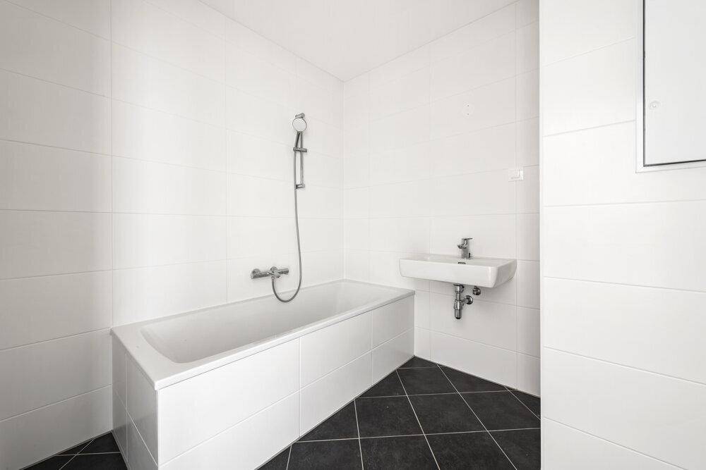 Modernes Badezimmer mit Badewanne, Waschbecken und weißen Fliesen an den Wänden.