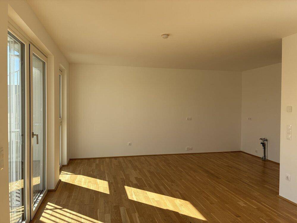 Geräumiges Zimmer mit Parkettboden und viel Tageslicht durch große Fenster.