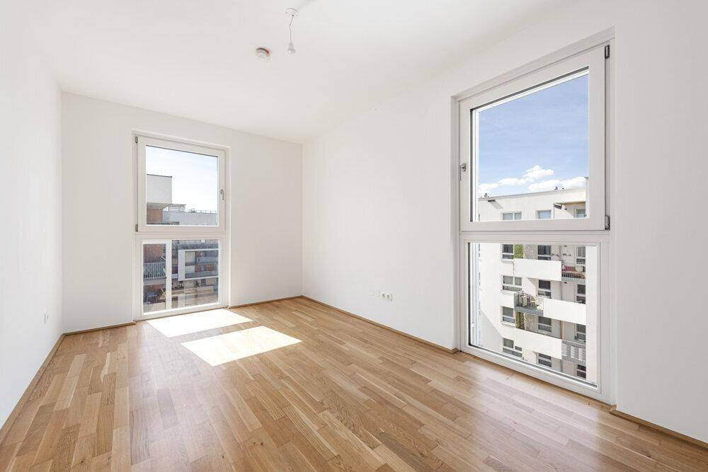 Helles Zimmer mit zwei großen Fenstern und Holzboden, bietet einen weiten Blick.