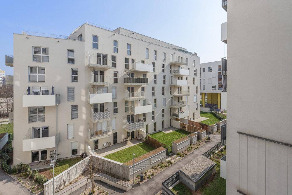 Moderne Wohnanlage mit mehreren Balkonen und kleinen privaten Gärten im Erdgeschoss.