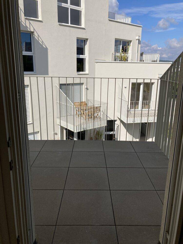 Geräumiger Balkon mit Blick auf andere Balkone und die moderne Architektur des Gebäudes.