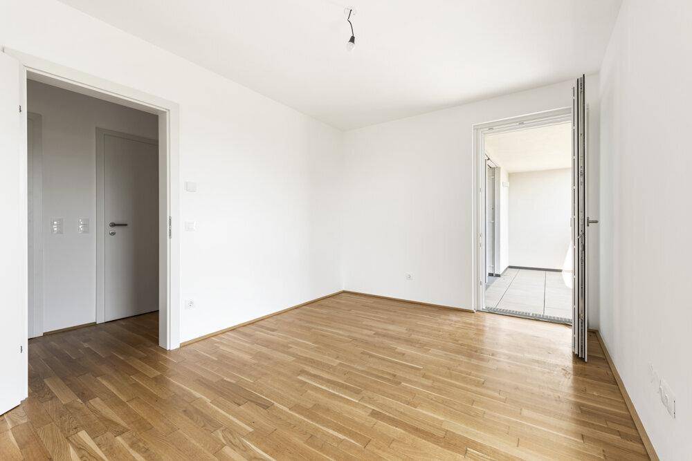 Helles Zimmer mit Holzboden und Zugang zu einem Außenbereich, ideal für Entspannung.
