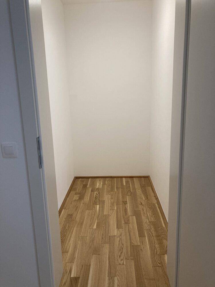 Kleiner, leerer Raum mit Parkettboden und weißen Wänden, ideal als Abstellraum oder begehbarer Kleiderschrank.