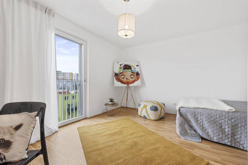 Schlafzimmer mit Holzboden und großem Fenster, das viel Licht hereinlässt und einen französischen Balkon bietet.