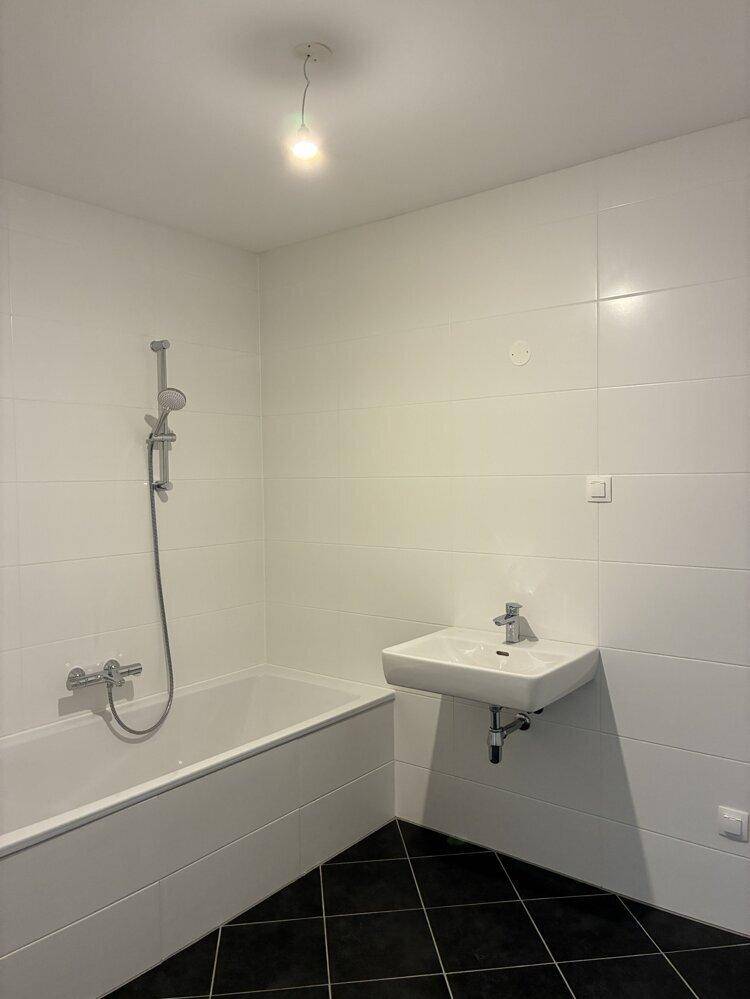 Modernes Badezimmer mit weißen Wandfliesen, Badewanne und einem einzelnen Waschbecken.
