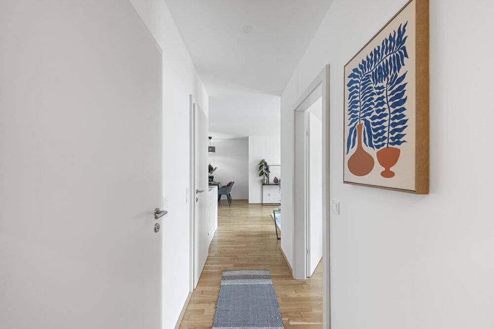 Heller Flur mit Holzboden und einem modernen Kunstwerk an der Wand.