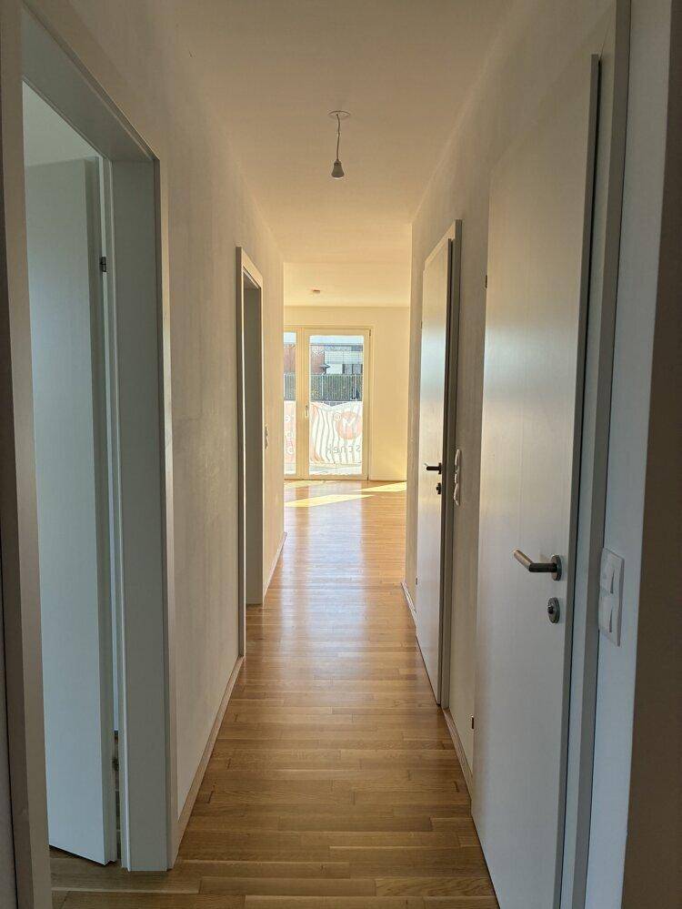 Heller Flur mit Parkettboden, der zu den verschiedenen Zimmern der Wohnung führt.