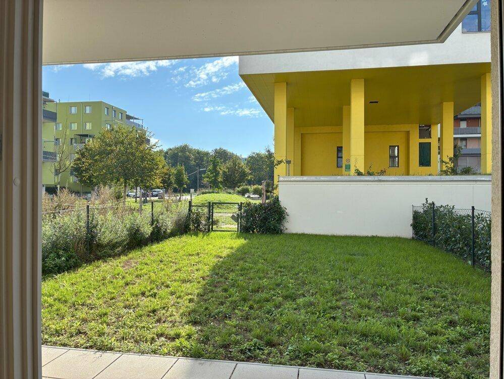 Privater Gartenbereich mit Rasenfläche und Blick auf die umliegenden modernen Gebäude.