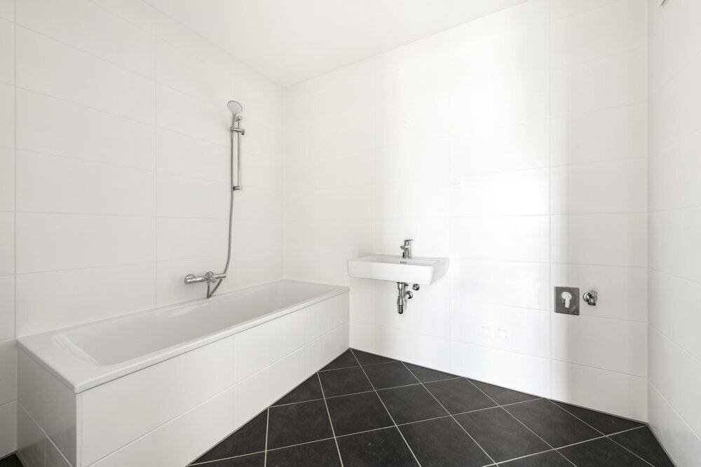 Modernes Badezimmer mit Badewanne, Waschbecken und weißen Fliesen, sehr sauber.