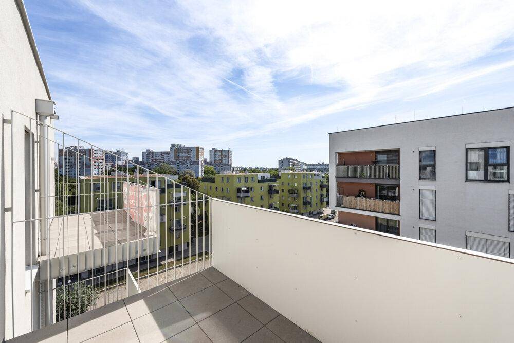 Breiter Balkon mit Fliesenboden und umfassendem Blick auf die städtische Umgebung.