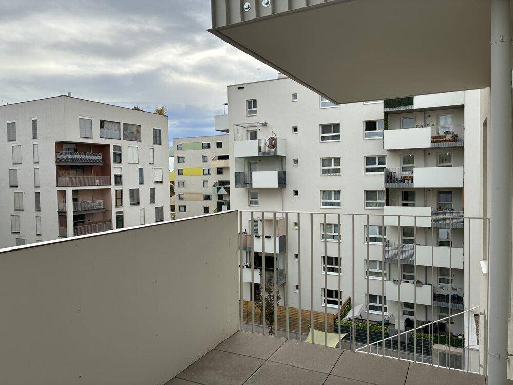 Geräumiger Balkon mit Fliesenboden und Blick auf die modernen Wohngebäude.