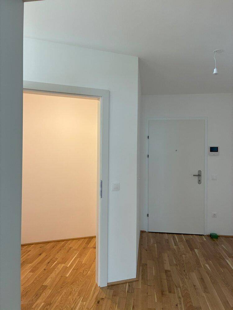 Eingangsbereich mit Parkettboden und weißer Eingangstür, die zu den Wohnräumen führt.