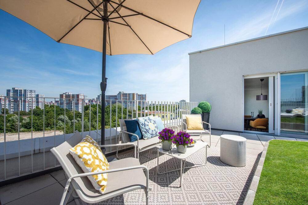 Einladende Dachterrasse mit bequemen Sitzgelegenheiten, Sonnenschirm und weitem Blick über die Stadt.