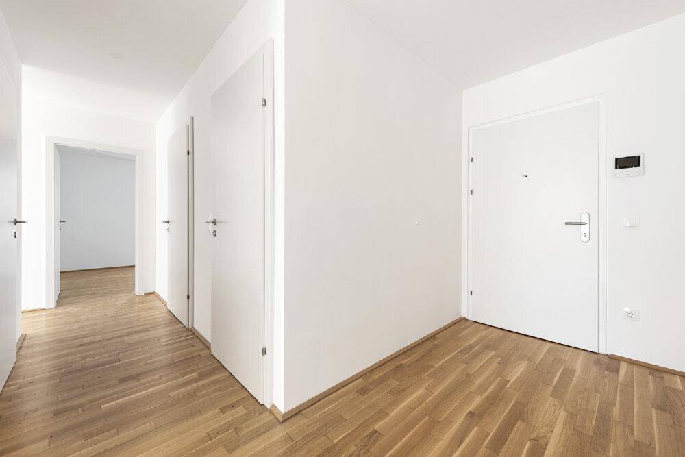 Heller Flur mit Holzboden und mehreren weißen Türen, die zu den Zimmern führen.