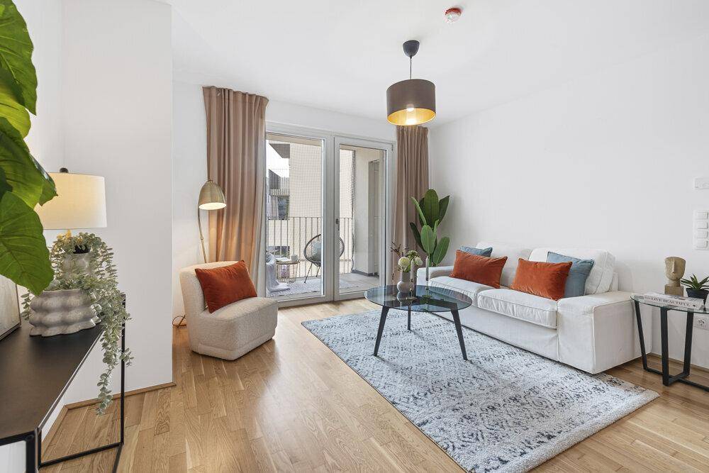 Helles Wohnzimmer mit bequemen Möbeln und direktem Zugang zu einem Balkon.