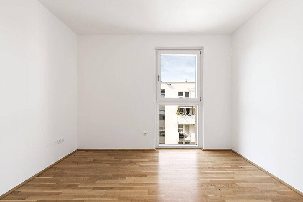 Ruhiges Schlafzimmer mit Holzboden und einem großen Fenster mit Blick auf die Umgebung.