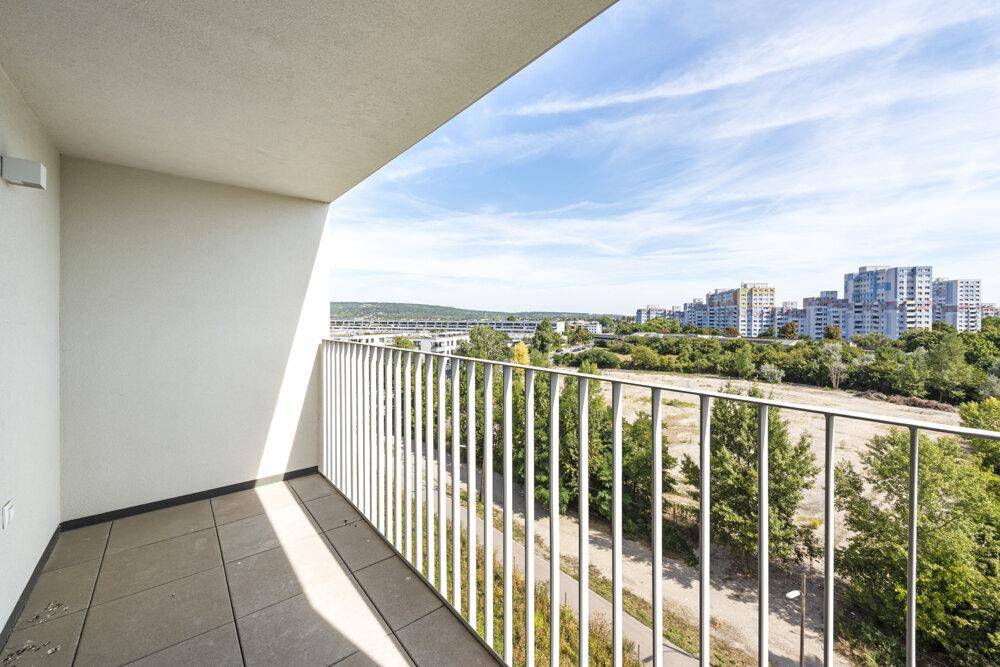 Heller Balkon mit Fliesenboden und weitem Blick auf die grüne Umgebung und Stadt.