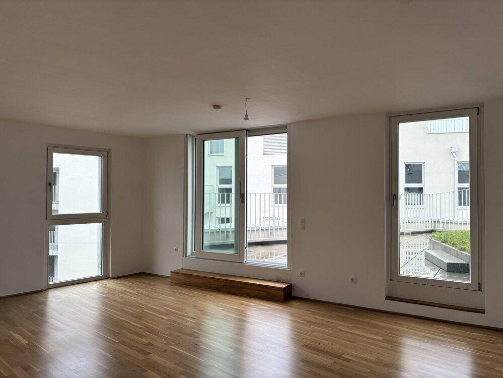 Lichtdurchflutetes Wohnzimmer mit Holzboden und Blick auf den Innenhof.