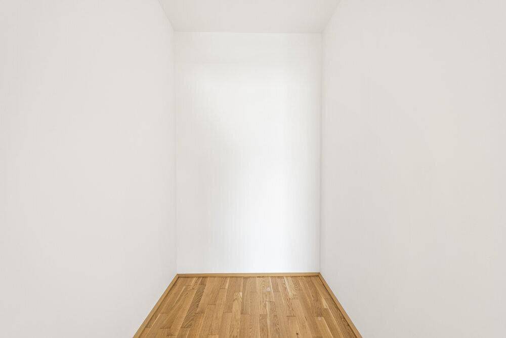 Kleiner, leerer Raum mit Holzboden, ideal als Abstellraum oder begehbarer Kleiderschrank.