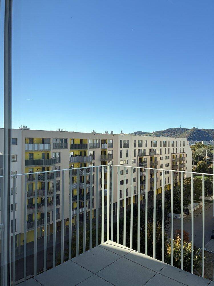 Weitläufiger Blick von einem Balkon auf eine moderne Wohnanlage und die umliegende Berglandschaft.