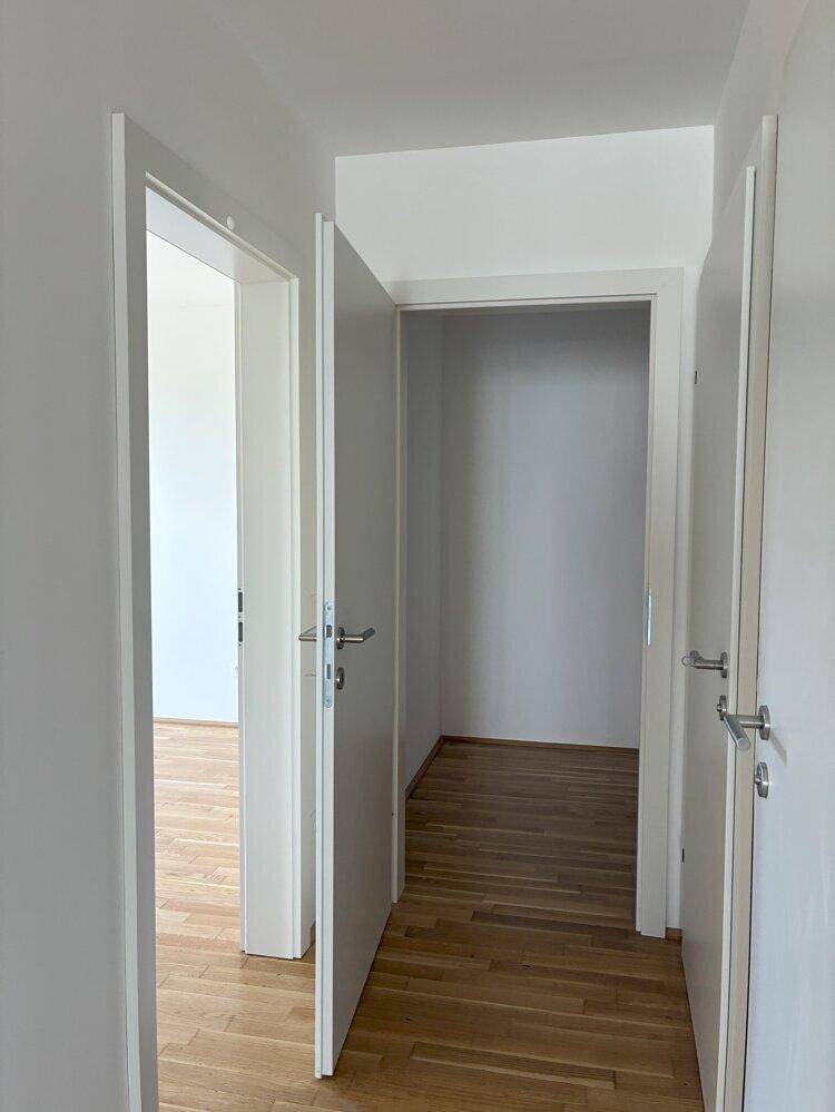 Heller Flur mit offenen Türen, die den Zugang zu verschiedenen Zimmern ermöglichen.