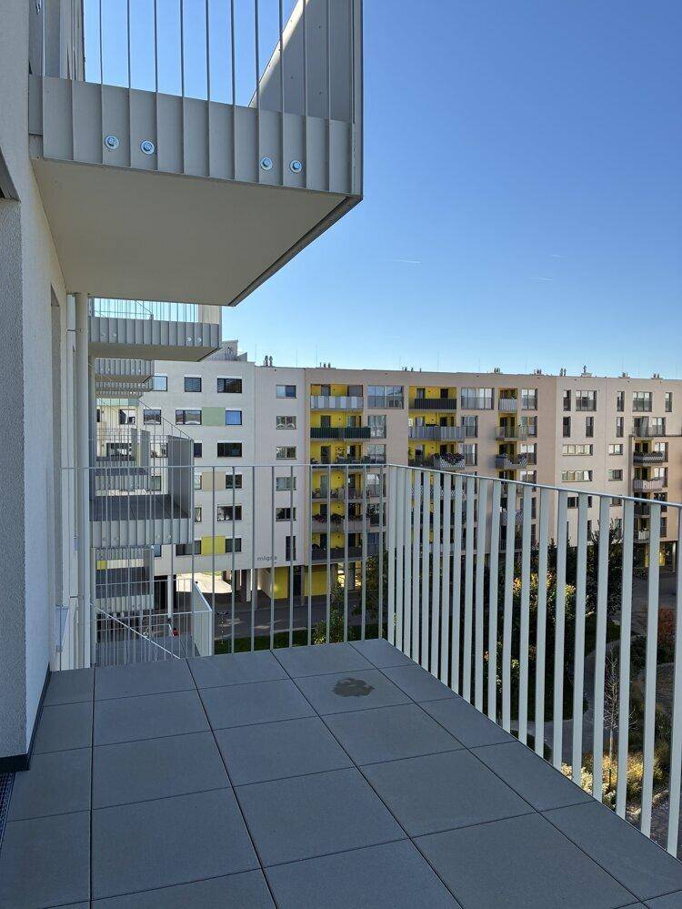 Geräumiger Balkon mit Fliesenboden und weitem Blick auf den Innenhof und die Nachbargebäude.
