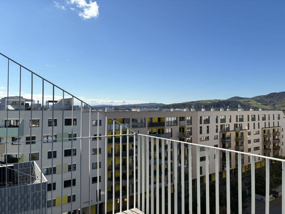 Geräumiger Balkon mit Fliesenboden und Panoramablick auf die Stadt und die grüne Landschaft.