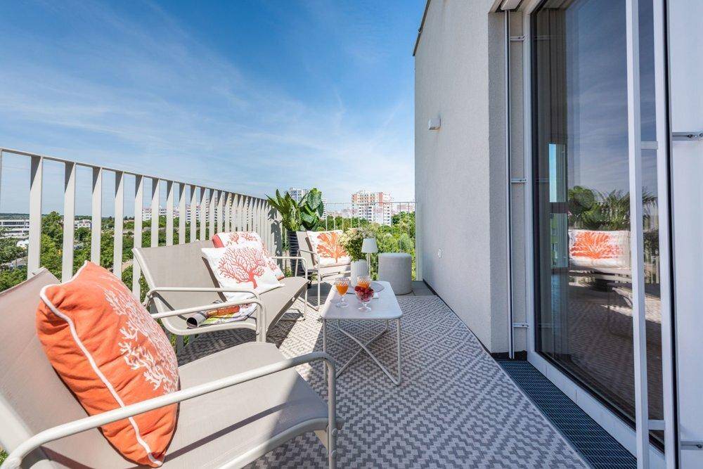 Heller Balkon mit bequemen Sitzmöbeln und großem Fenster, das viel Tageslicht in den Innenbereich lässt.