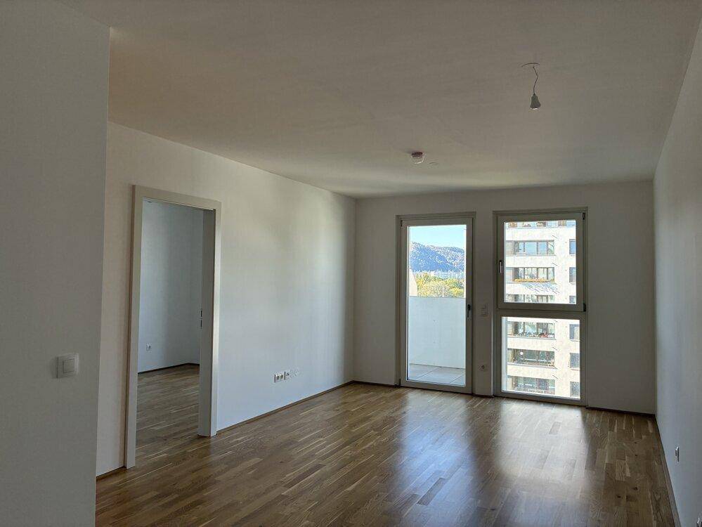 Geräumiger Wohnbereich mit Parkettboden, großen Fenstern und einem weiten Blick auf die Umgebung.