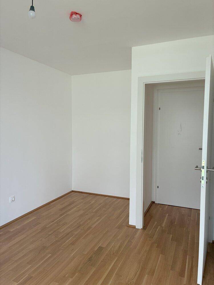 Unmöblierter Raum mit Holzboden und weiß gestrichenen Wänden, ideal als Schlaf- oder Arbeitszimmer.