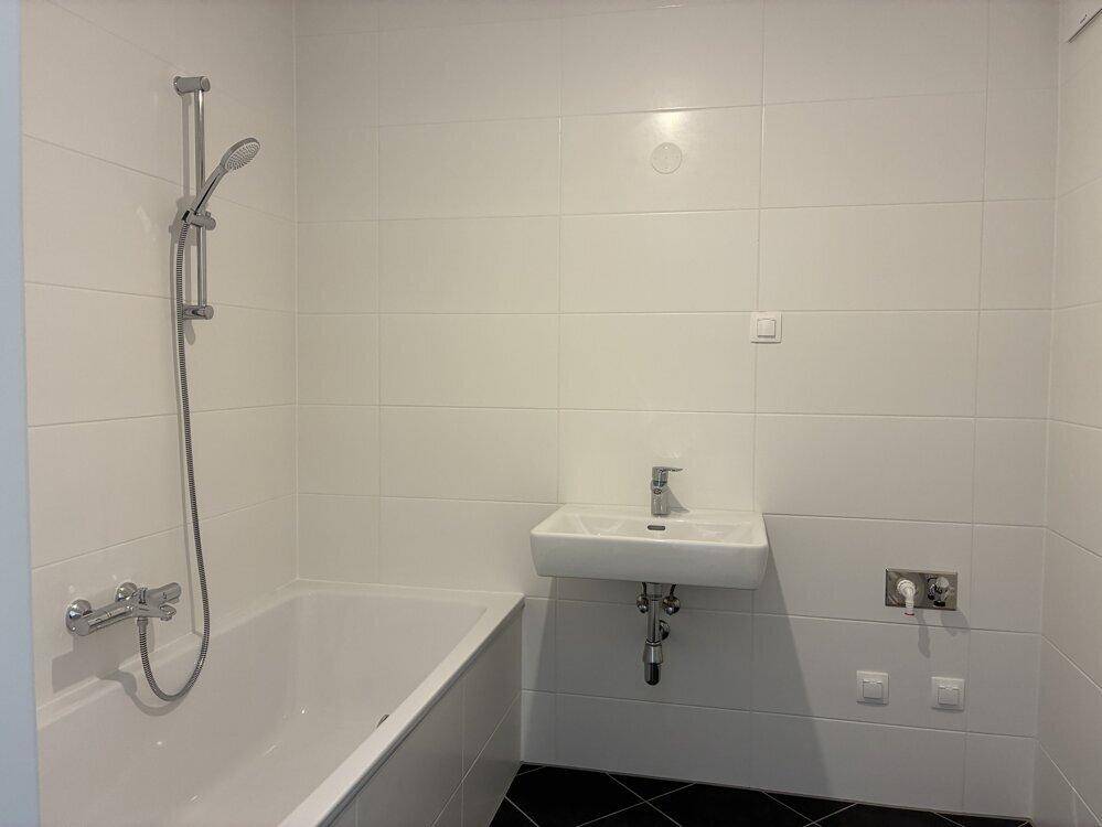 Modernes Badezimmer mit Badewanne, Duschvorrichtung und weißen Wandfliesen.