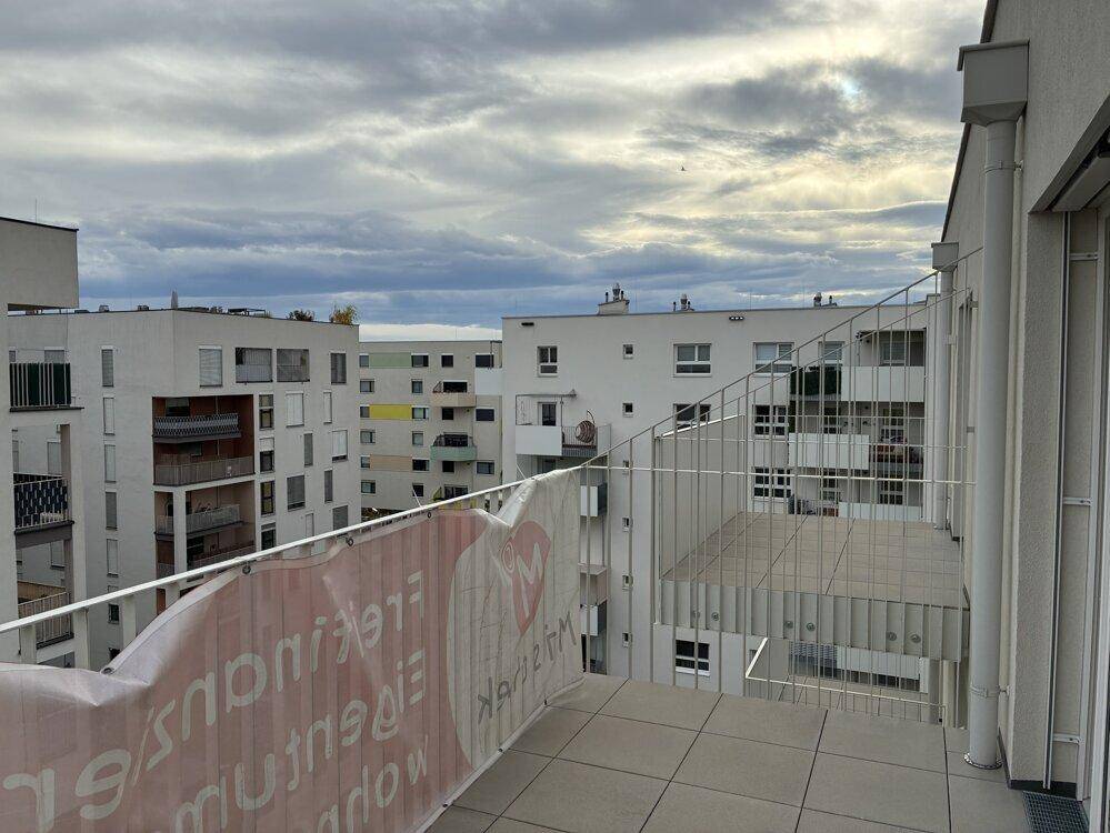Geräumiger Balkon mit Fliesenboden und Blick auf die moderne Architektur der Umgebung.