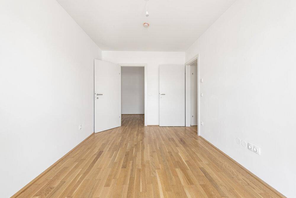 Helles Zimmer mit Parkettboden und zwei Türen, bietet flexible Nutzungsmöglichkeiten.