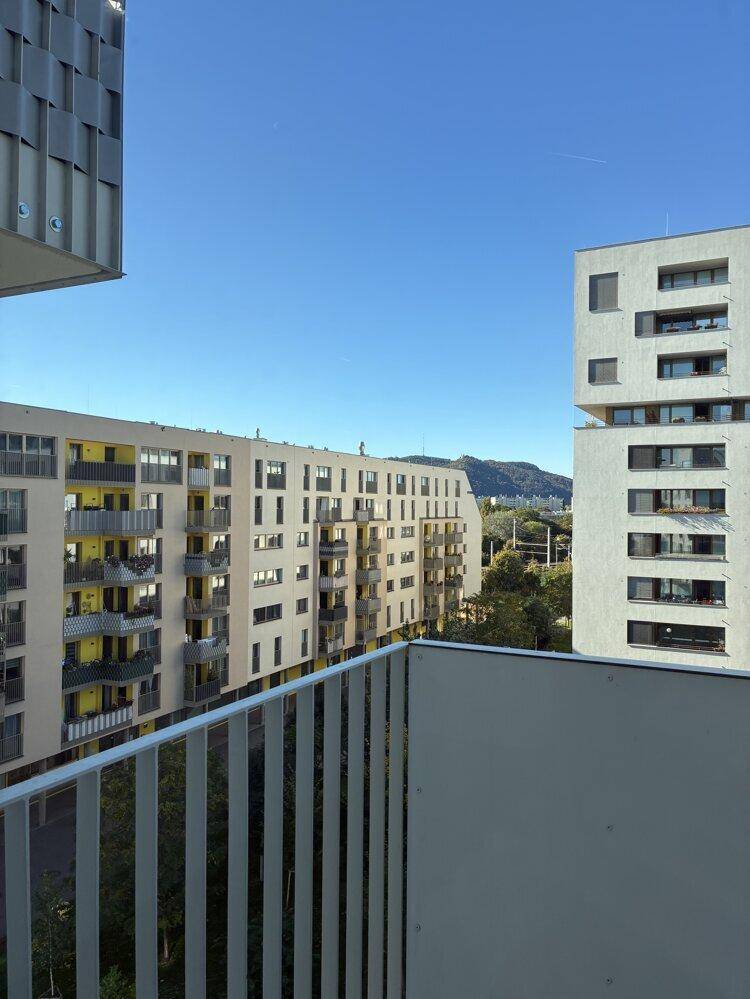 Weiter Blick von einem Balkon über die Dächer der Stadt und die umliegenden Berge.