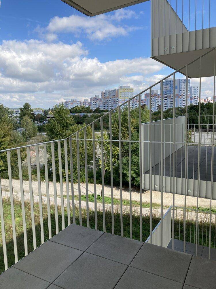 Balkon mit Stadtblick und grüner Umgebung, umgeben von modernen Wohngebäuden.