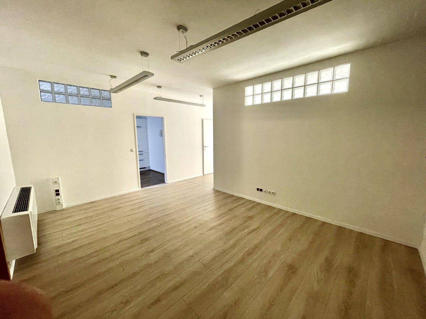 Heller Büroraum mit Glasbausteinen für zusätzliches Licht und modernem Laminatboden.