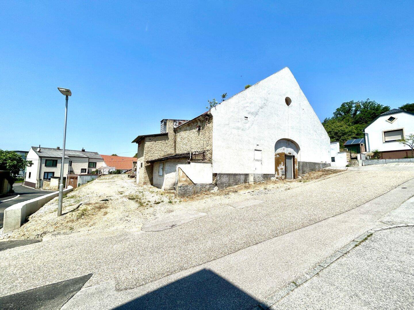 Seitenansicht des alten Gebäudes mit verputzter und steinerner Fassade an einer Straße.