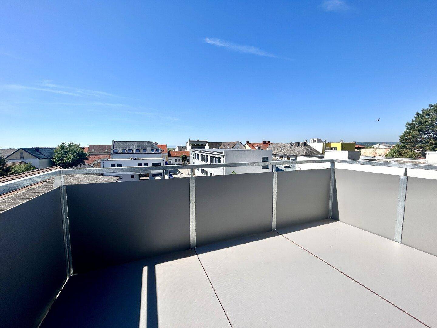 Geräumiger Balkon mit Blick auf die umliegenden Gebäude und den blauen Himmel.
