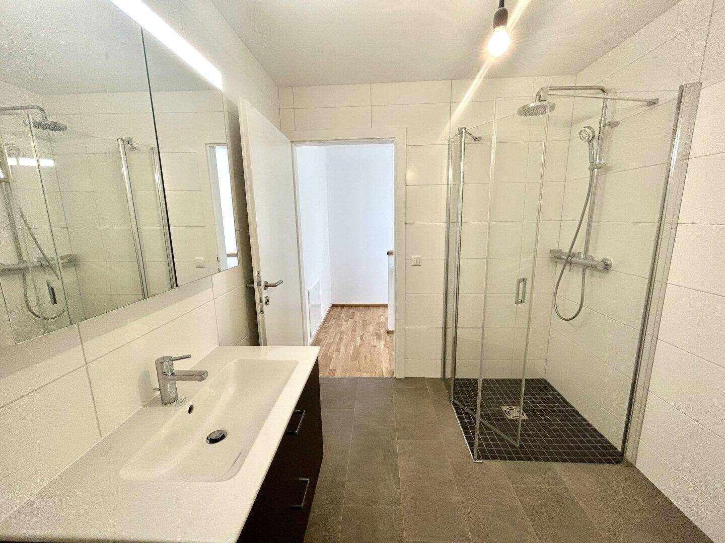 Modernes Badezimmer mit ebenerdiger Dusche, Einzelwaschbecken und Spiegelschrank.